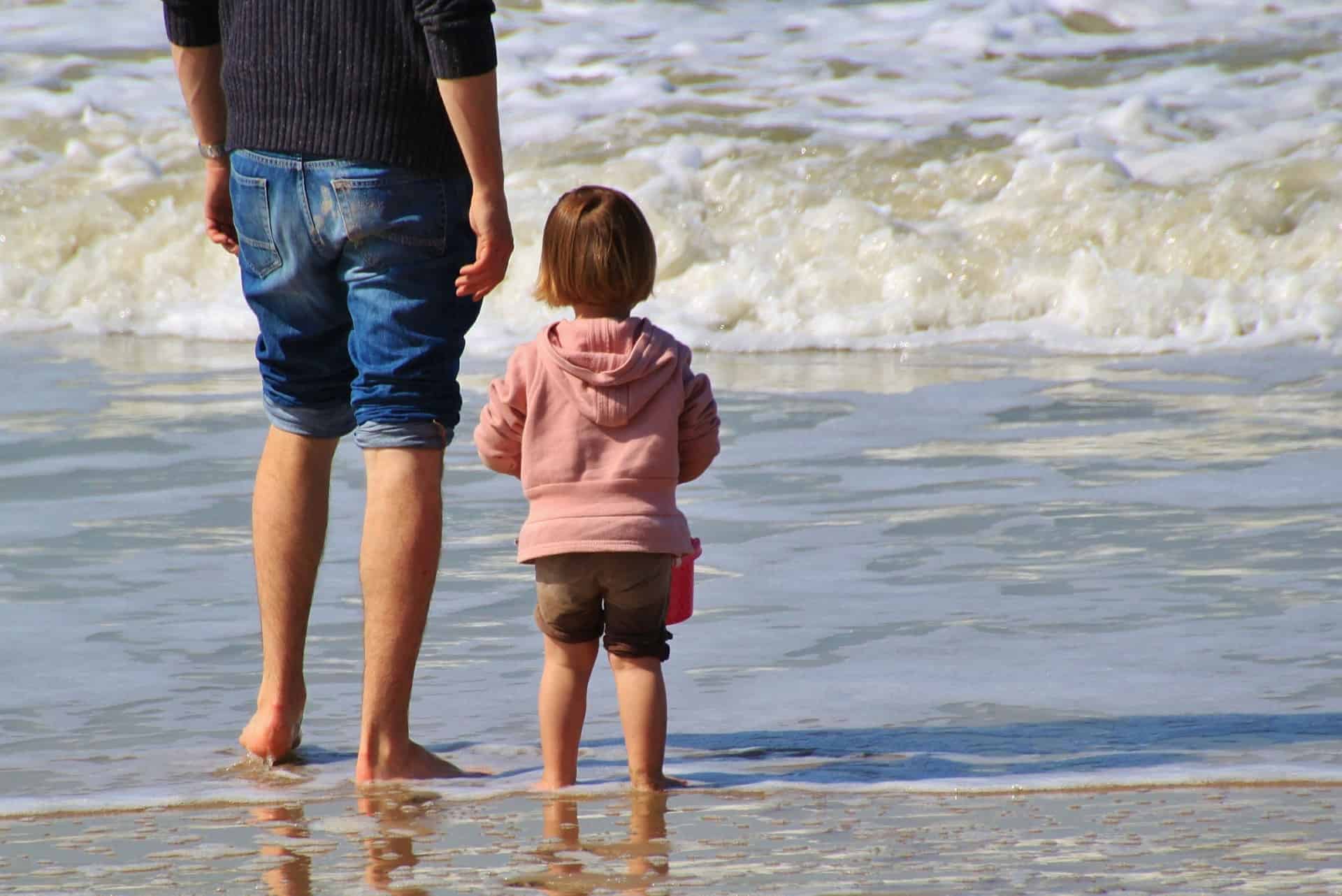 Man and child standing by the sea.