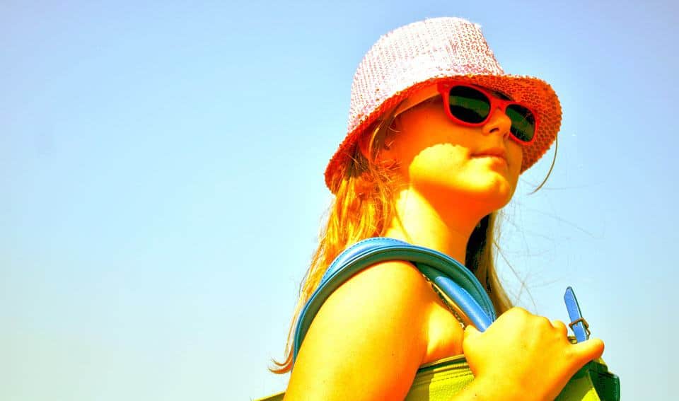 Woman wearing sunglasses and hat holding a bag