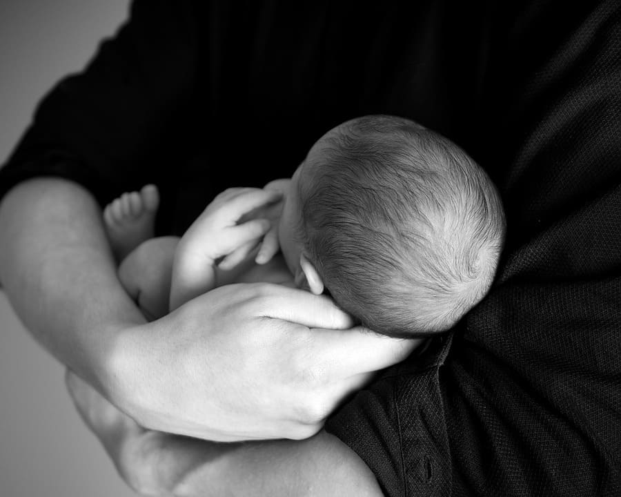 Adult cradling a newborn baby.