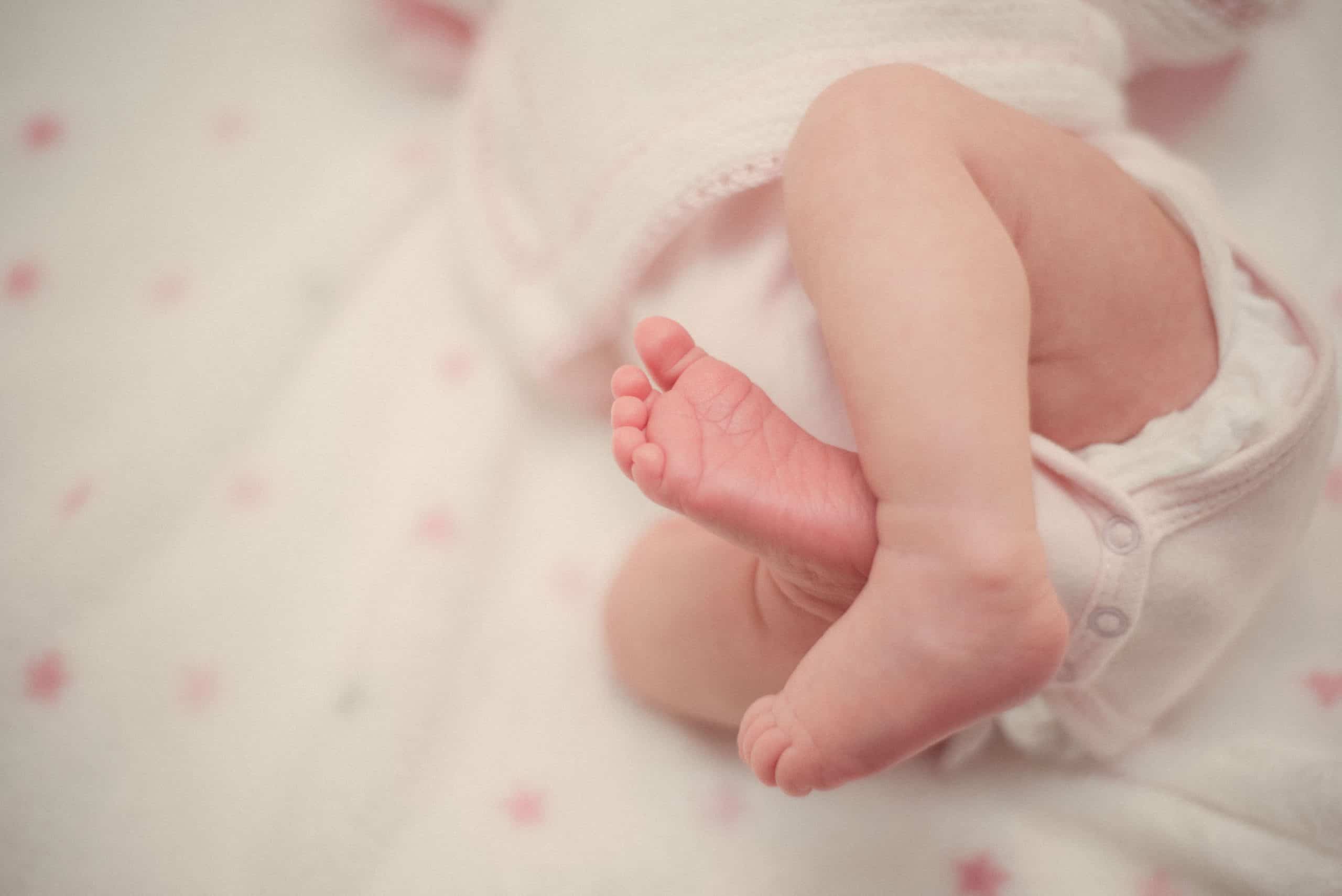 Newborn baby's feet in white onesie